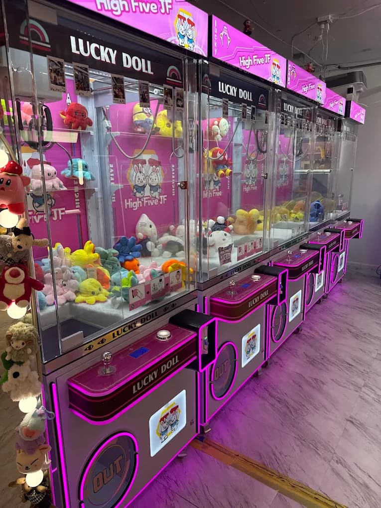A row of pink-lit claw machines filled with plush toys at imizzu
